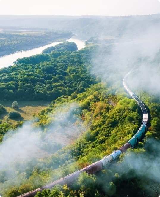 moving train on railway with high column of smoke flowing river hills and railway on the foreground